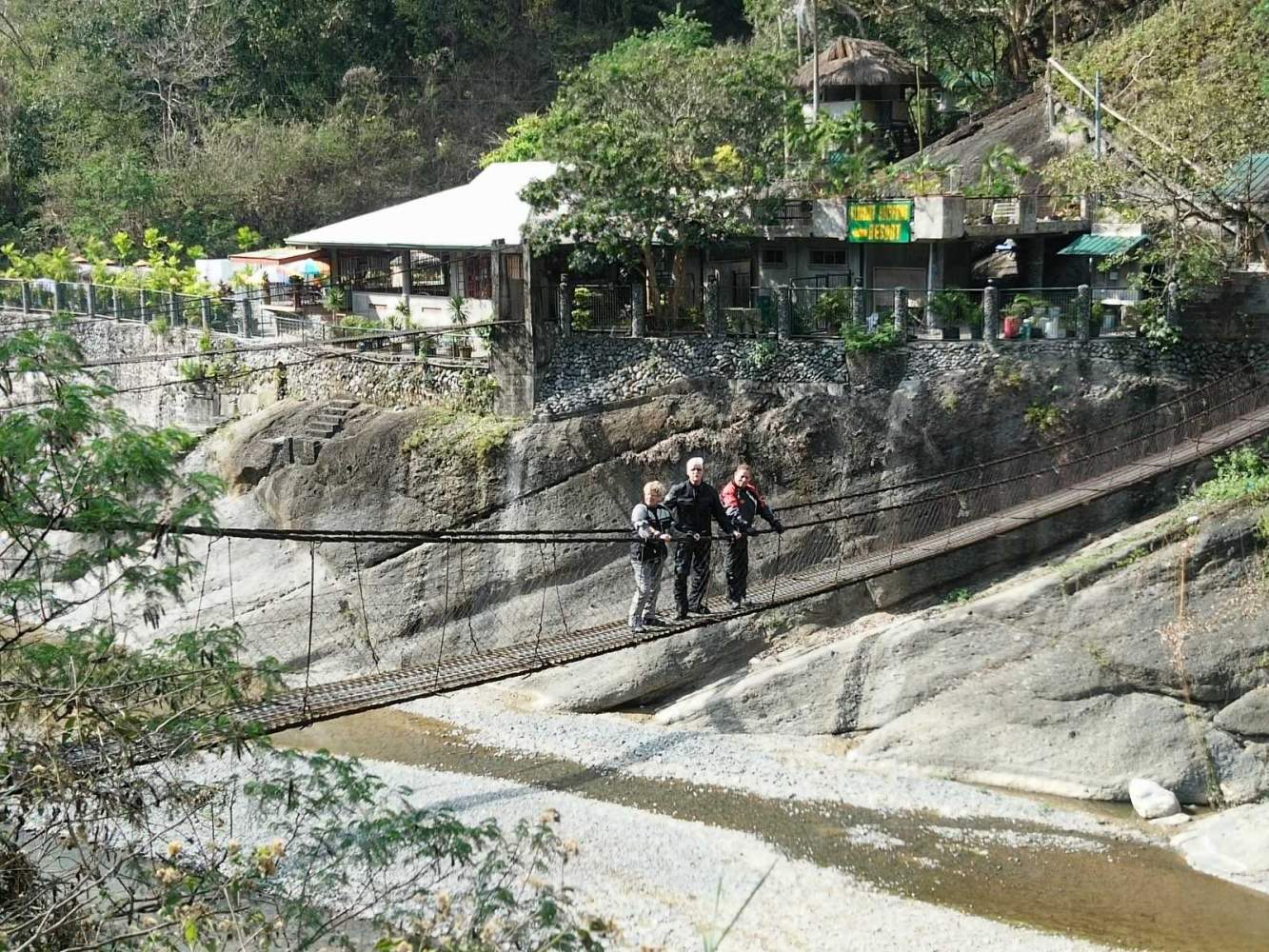 Auf dem Weg nach Baguio haben wir die Möglichkeit in einem Restaurant zu essen, das nur über eine schmale Hängebrücke zu Fuß erreichbar ist. Unter uns liegt das Flussbett und die wackelige Angelegenheit ist eher was für die mutigen Motorradfahrer/innen unter uns.